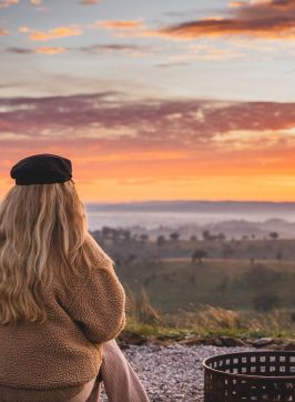 Woman enjoying the firepit while watching the sunrise from the Uralla Tent at Sierra Escape, Piambong