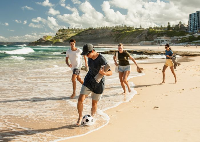 Friends enjoying game of soccer, Newcastle Beach