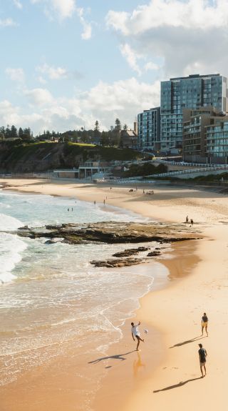 Friends playing on Newcastle Beach, Newcastle